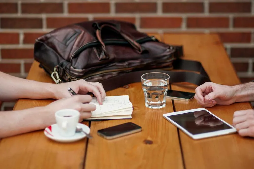 Zwei Personen besprechen Notizen an einem Tisch, dazu Tablet und Smartphone